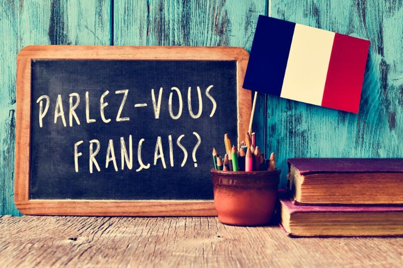 A French flag and a chalkboard with "parlez-vous français" written on it