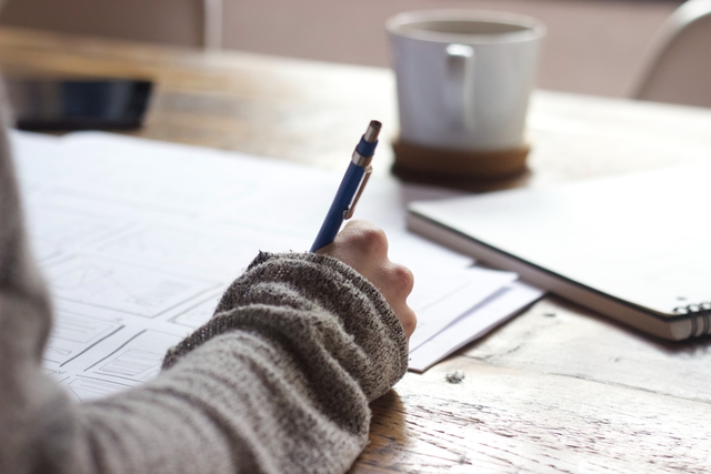 A person writing on paper with a pen