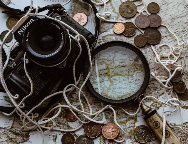 Camera, magnifying glass, coins, and map