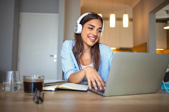 Girl working on a laptop and wearing headphones